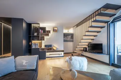 a living room with a staircase and a couch at Duplex avec sauna et vue Mont Blanc au centre de Chamonix in Chamonix-Mont-Blanc