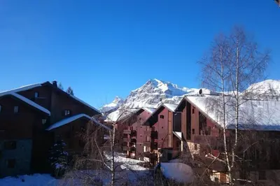 a group of buildings with a snow covered mountain in the background at GREEN APPLE CARROZ Duplex WIFI Garage Balcon-Sud Vue Montagne in Les Carroz d'Araches