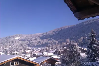 a snow covered village with a mountain in the background at Les Carroz Alpine Chalet - central in Les Carroz d'Araches
