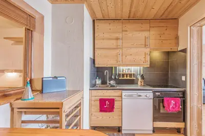a kitchen with wooden cabinets and a wooden table at Appartement Mazot - Welkeys in Megève