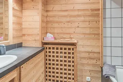 a bathroom with a sink and a wooden wall at Appartement Mazot - Welkeys in Megève