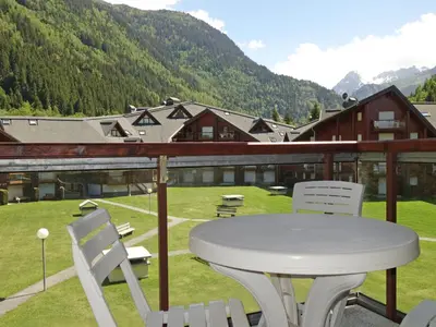 a white table and chairs on a balcony with mountains at Studio L'Enclave I et J-28 by Interhome in Les Contamines-Montjoie