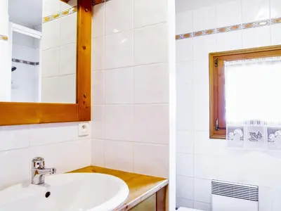 a white bathroom with a sink and a window at Apartment Les Capucins by Interhome in Chamonix-Mont-Blanc