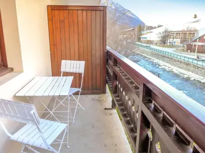 two chairs and a table on a balcony with a view of train tracks at Studio Les Jardins du Mont-Blanc-4 by Interhome in Chamonix-Mont-Blanc