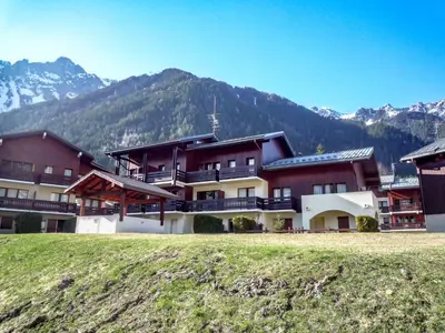 a large building with mountains in the background at Studio Les Jardins du Mont-Blanc-4 by Interhome in Chamonix-Mont-Blanc