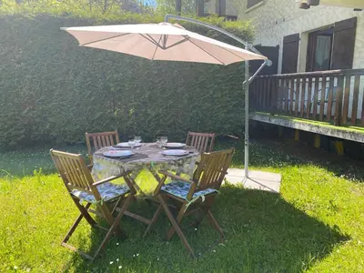 a table with two chairs and an umbrella at Appartement lumineux et cosy en rez de jardin in Saint-Gervais-les-Bains