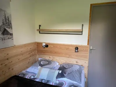 a small bedroom with a bed in the corner at Appartement lumineux et cosy en rez de jardin in Saint-Gervais-les-Bains
