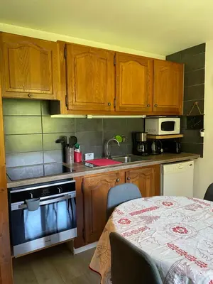 a small kitchen with wooden cabinets and a table with a table at Appartement lumineux et cosy en rez de jardin in Saint-Gervais-les-Bains
