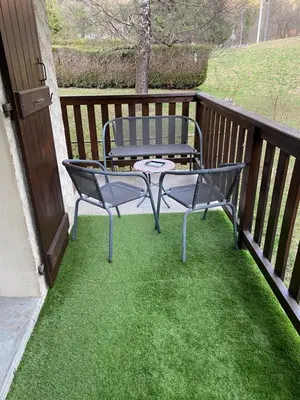 a chair and a table on a balcony at Appartement lumineux et cosy en rez de jardin in Saint-Gervais-les-Bains