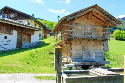 a wooden hut in a field next to a house at Authenthic Chalet Ski on Les Houches Chamonix in Les Houches