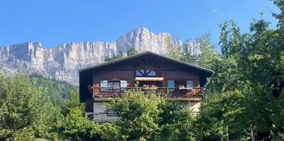 a house with a balcony with a mountain in the background at Chalet du grand cerf in Servoz