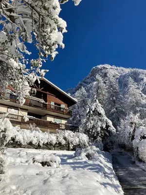 a building covered in snow next to a mountain at Chalet du grand cerf in Servoz