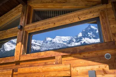 a view of the mountains through a window in a log cabin at Chalet Plan Glacier in Chamonix-Mont-Blanc