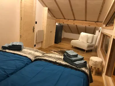 a bedroom with a blue bed and a white chair at Chalet Plan Glacier in Chamonix-Mont-Blanc
