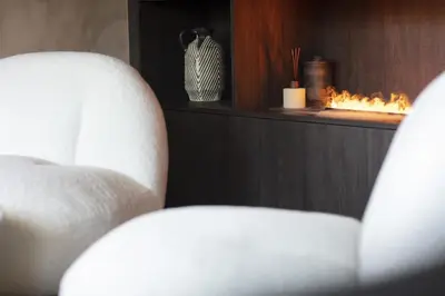 a white chair in a room with a fireplace at Apartment FERRONNE by JAPANDI home in Megève