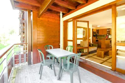 a table and chairs on the balcony of a house at Spacious Family 2-bed, 2-bath with parking, private piste in Flaine