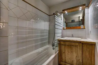 a bathroom with a tub and a sink and a mirror at MGM Parc Couttet in Chamonix-Mont-Blanc