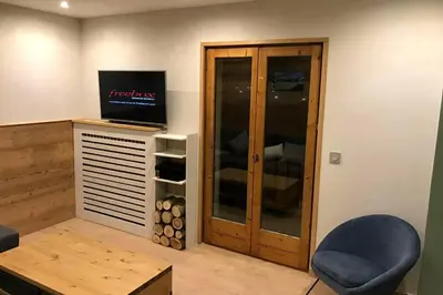 a living room with a tv and a blue chair at *** Le Refuge *** Logement standing Megève in Demi-Quartier