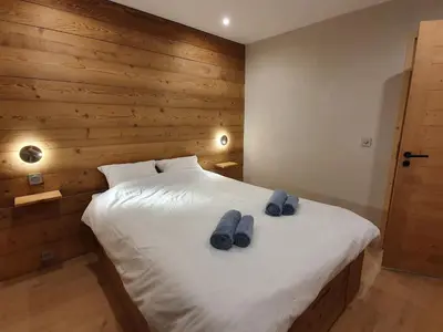 a bedroom with a bed with two blue slippers on it at *** Le Refuge *** Logement standing Megève in Demi-Quartier
