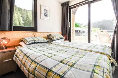 a bedroom with two beds and a large window at Penthouse 3-bedroom apartment, mountain views, large terrasse, piste access in Flaine