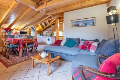 a living room with a blue couch and a table at Le Hameau des Neiges in Les Houches