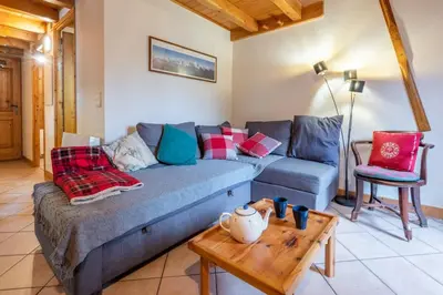 a living room with a blue couch and a table at Le Hameau des Neiges in Les Houches