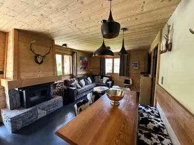 a living room with a wooden table and a fireplace at Chalet Megeve, idéal familles proche ski et centre village in Megève