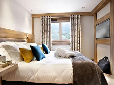 a bedroom with a white bed with pillows and a window at MGM Hôtels & Résidences - Résidence Chalets Laska in Les Contamines-Montjoie