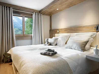 a bedroom with a large white bed with a teddy bear on it at MGM Hôtels & Résidences - Résidence Chalets Laska in Les Contamines-Montjoie
