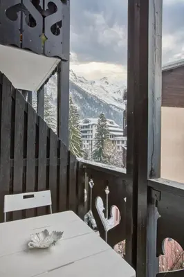 a table on a balcony with a view of a mountain at Apartment Mont du Soleil - Central Chamonix Mont Blanc in Chamonix-Mont-Blanc