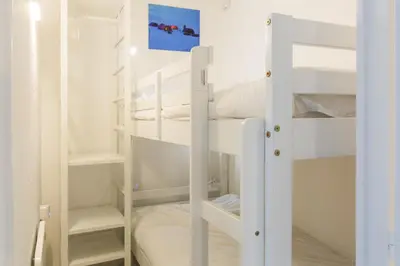 a room with two bunk beds with white walls at Apartment Mont du Soleil - Central Chamonix Mont Blanc in Chamonix-Mont-Blanc