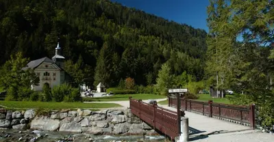 a bridge over a river with a church in the background at Bel appartement au décor Montagnard - 80m2 in Les Contamines-Montjoie