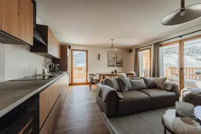 a living room with a couch and a kitchen at Le Refuge des Anges in Megève