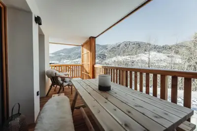 a wooden deck with a table and a chair on it at Le Refuge des Anges in Megève