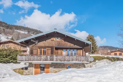 a log house with a balcony in the snow at Le Chalet des Neiges - Welkeys in Megève
