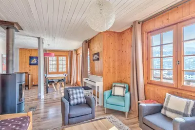a living room with wooden walls and furniture and windows at Le Chalet des Neiges - Welkeys in Megève