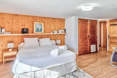 a bedroom with a large bed and wooden walls at Le Chalet des Neiges - Welkeys in Megève