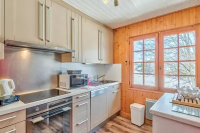 a kitchen with white appliances and wooden walls at Le Chalet des Neiges - Welkeys in Megève