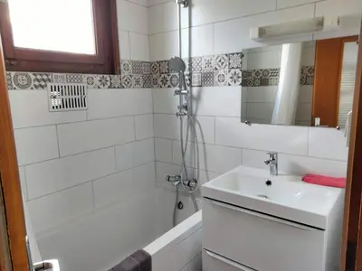 a bathroom with a sink and a tub and a mirror at Le clair logis in Sixt