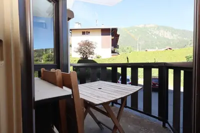 a wooden table and chairs on a balcony with a view at Résidence Prarion 1 - Prarion 2 MAE-4874 in Les Houches