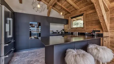 a kitchen with a counter with two white furry stools at Chalet Hupa in Les Houches