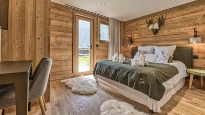 a bedroom with wooden walls and a bed with stuffed animals on it at Chalet Hupa in Les Houches