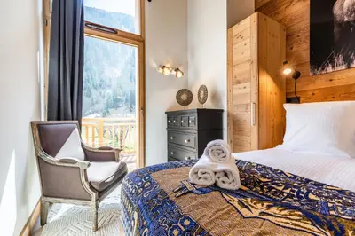 a bedroom with a bed and a chair and a window at Sapelli apartment Argentière Chamonix - by EMERALD STAY in Chamonix-Mont-Blanc