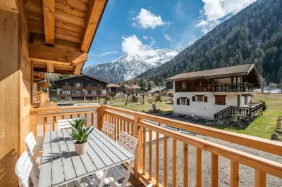 a wooden balcony with a table and a view of a mountain at Sapelli apartment Argentière Chamonix - by EMERALD STAY in Chamonix-Mont-Blanc