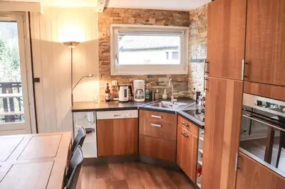 a small kitchen with wooden cabinets and a window at Appartement Lyret centre Chamonix, Vue d'exception in Chamonix-Mont-Blanc