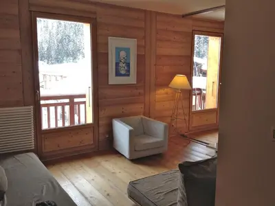 a living room with a chair and two windows at Appartement Arolles in Chamonix-Mont-Blanc