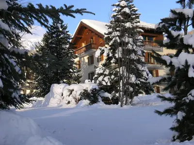 a building with snow covered trees in front of it at Appartement Arolles in Chamonix-Mont-Blanc