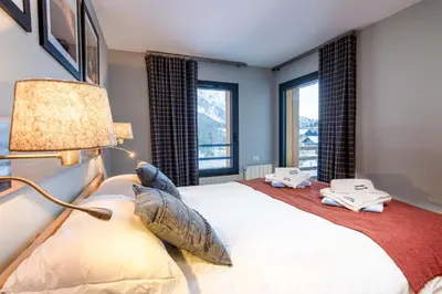 a bedroom with a bed with a lamp and windows at La Cordee 124 Apartment - Chamonix All Year in Chamonix-Mont-Blanc