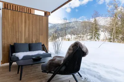 a patio with a chair and a couch in the snow at Interlude Megeve in Megève