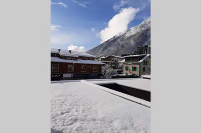 a snow covered roof with buildings and a mountain at Chamonix centre - WIFI - Parking - Rés Aiguille du midi in Chamonix-Mont-Blanc